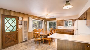 A kitchen with wooden cabinets, a dining table with chairs, a ceiling fan, and a refrigerator.