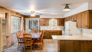 A kitchen with wooden cabinets, a white refrigerator, a microwave, and a dining table with chairs.