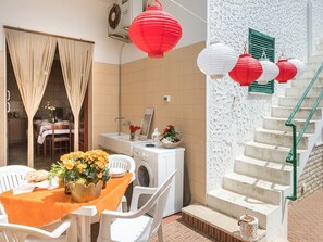 Comedor con una mesa lista para dos, lavadora y una escalera decorada con faroles rojos.