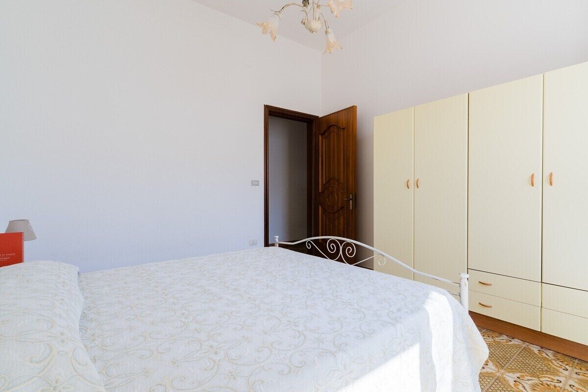 Ein Schlafzimmer mit einem Bett, einem Kleiderschrank und einer Tür zu einem anderen Raum.