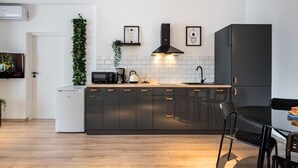 A modern kitchen with dark cabinets, a microwave, a kettle, and a sink. - Esiko by MRG Apartments | Balcony | University Square | Old Town | City Centre (București)