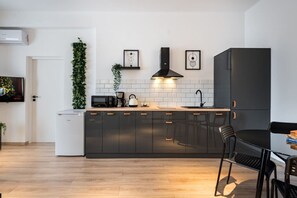 Moderni keittiö, jossa on tummat kaapit, mikroaaltouuni, vedenkeitin ja pesuallas.