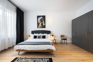 Een moderne slaapkamer met een groot bed, een nachtkastje, een stoel en een kledingkast.