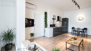 A modern apartment with a living room, dining area, kitchen, and a large window. - Esiko by MRG Apartments | Balcony | University Square | Old Town | City Centre (București)