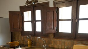 Eine Küche mit Holzschränken, einem Spülbecken und einem Fenster darüber.