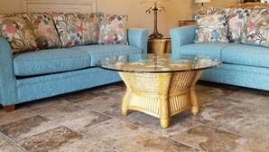 Ein Wohnzimmer mit zwei blauen Sofas, einem runden Couchtisch, einer Uhr und einem Kamin.