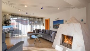 Una sala de estar moderna con chimenea, un sofá modular, una mesa de centro de vidrio y una televisión.