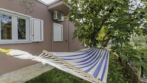 Un'amaca fissata tra due alberi in un giardino sul retro, con una casa sullo sfondo.