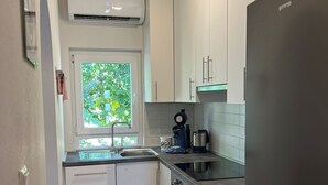 Una cucina moderna con mobili bianchi, un frigorifero in acciaio inossidabile, un forno integrato e una finestra vista verde.