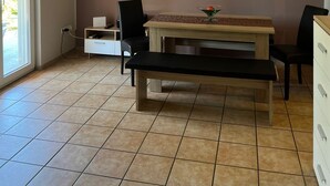Un'area pranzo con un tavolo e sedie in legno, una ventola a soffitto e un televisore a schermo piatto montato a parete.