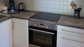 Una cucina con mobili bianchi, un forno nero, un piano cottura e una macchina per il caffè.