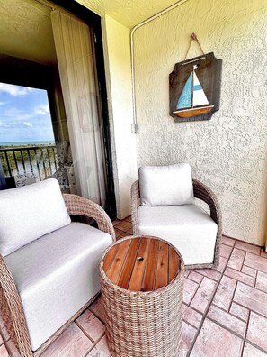 A balcony with wicker furniture and a small round table.