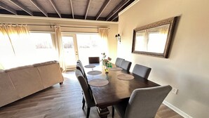 Un comedor con una mesa de madera, seis sillas y un espejo grande en la pared.