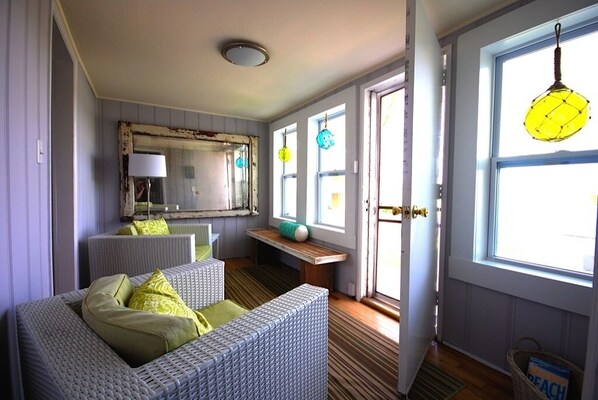 A room with wicker furniture, a mirror, and a window with a hanging light fixture.