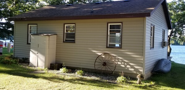 Une petite maison avec un garage, une grande roue et un plan d’eau en arrière-plan.