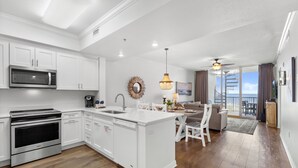 Una cocina moderna con armarios blancos, microondas integrado y una isla grande con pileta.