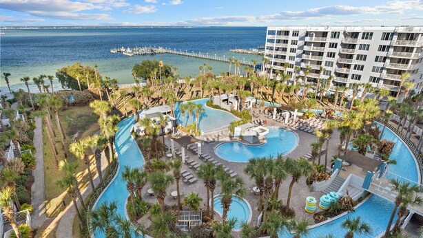 Un resort con varias piscinas, palmeras y vistas al océano.