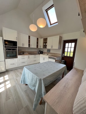 A modern kitchen with white cabinets, a large island, and a skylight.