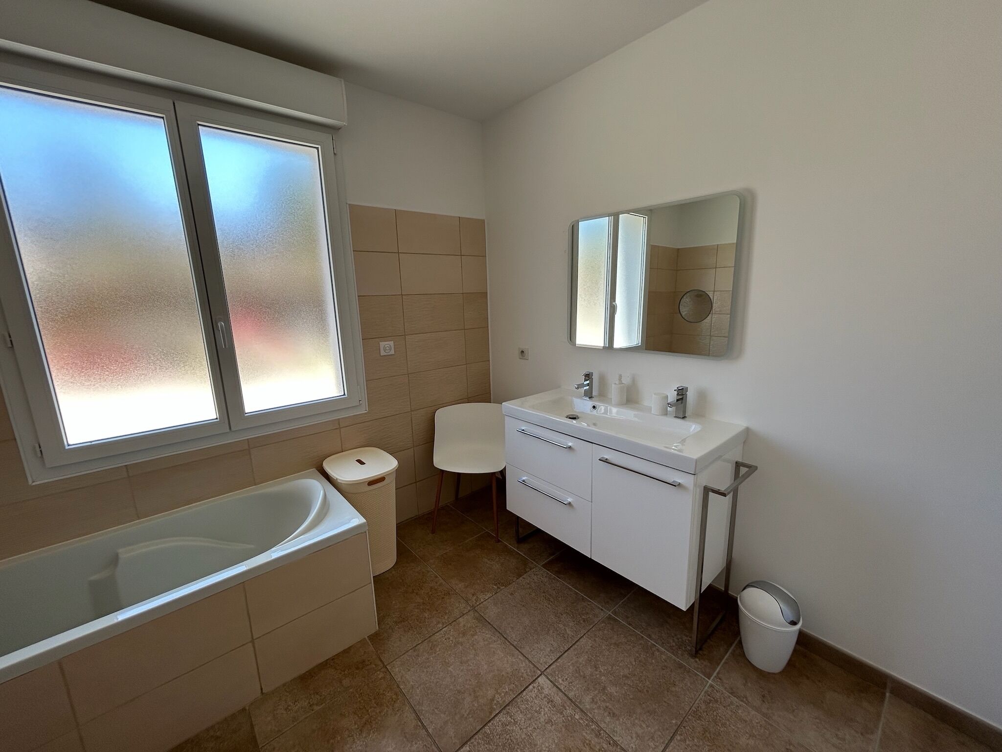 A modern bathroom with a bathtub, a vanity with a mirror, and a toilet.