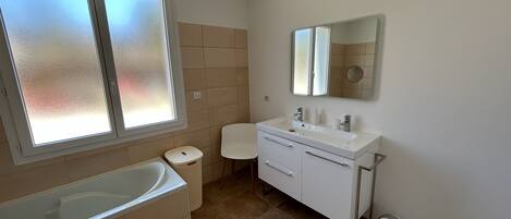 A modern bathroom with a bathtub, a vanity with a mirror, and a toilet.