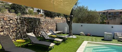 A rooftop pool area with lounge chairs, a small table, and a yellow umbrella.