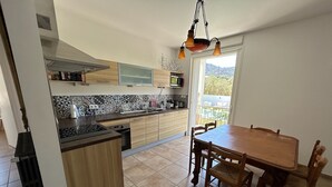 A modern kitchen with a central island, wooden cabinets, and a dining area with a table and chairs.