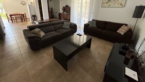 A living room with two sofas, a coffee table, and a dining area with a table and chairs.