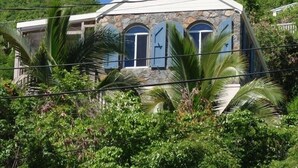 A house with a stone facade, multiple windows, and a sloped roof.