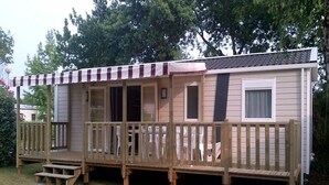 A mobile home with a porch, a covered entryway, and a small deck. - 3 Bedroom mobile home Siblu Domaine de Kerlann  Brittany France 131 (Pont-Aven)