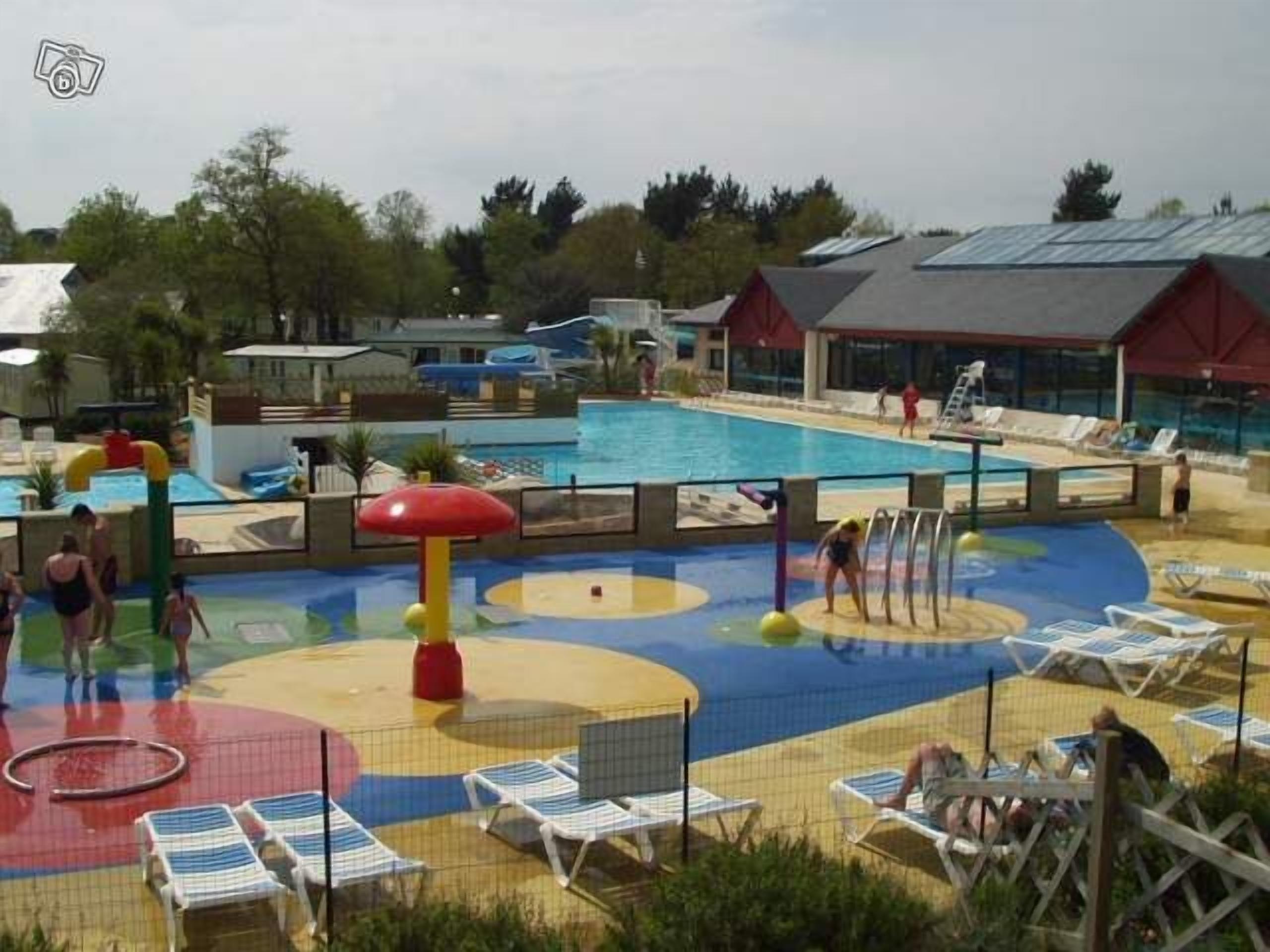 A pool area with multiple water play structures, a diving board, and lounge chairs.