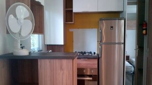 A compact kitchen with a built-in oven, a stainless steel refrigerator, and a wall-mounted fan. - 3 Bedroom mobile home Siblu Domaine de Kerlann  Brittany France 131 (Pont-Aven)