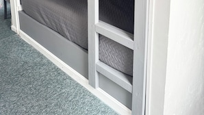A bunk bed with a pull-out desk and shelving unit, grey bedding, and a grey carpeted floor. - One Bedroom Apartment with Separate Bunk Bed Area (Shrewsbury)