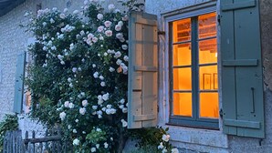 A rustic building with a window with wooden shutters, a wooden fence, and a wall covered with climbing roses. - Traditional French farmhouse for 10 guests, private pool, stunning country views (Montboyer)