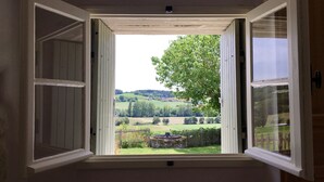 An open window with a view of a green landscape, a tree, and a stone structure. - Traditional French farmhouse for 10 guests, private pool, stunning country views (Montboyer)