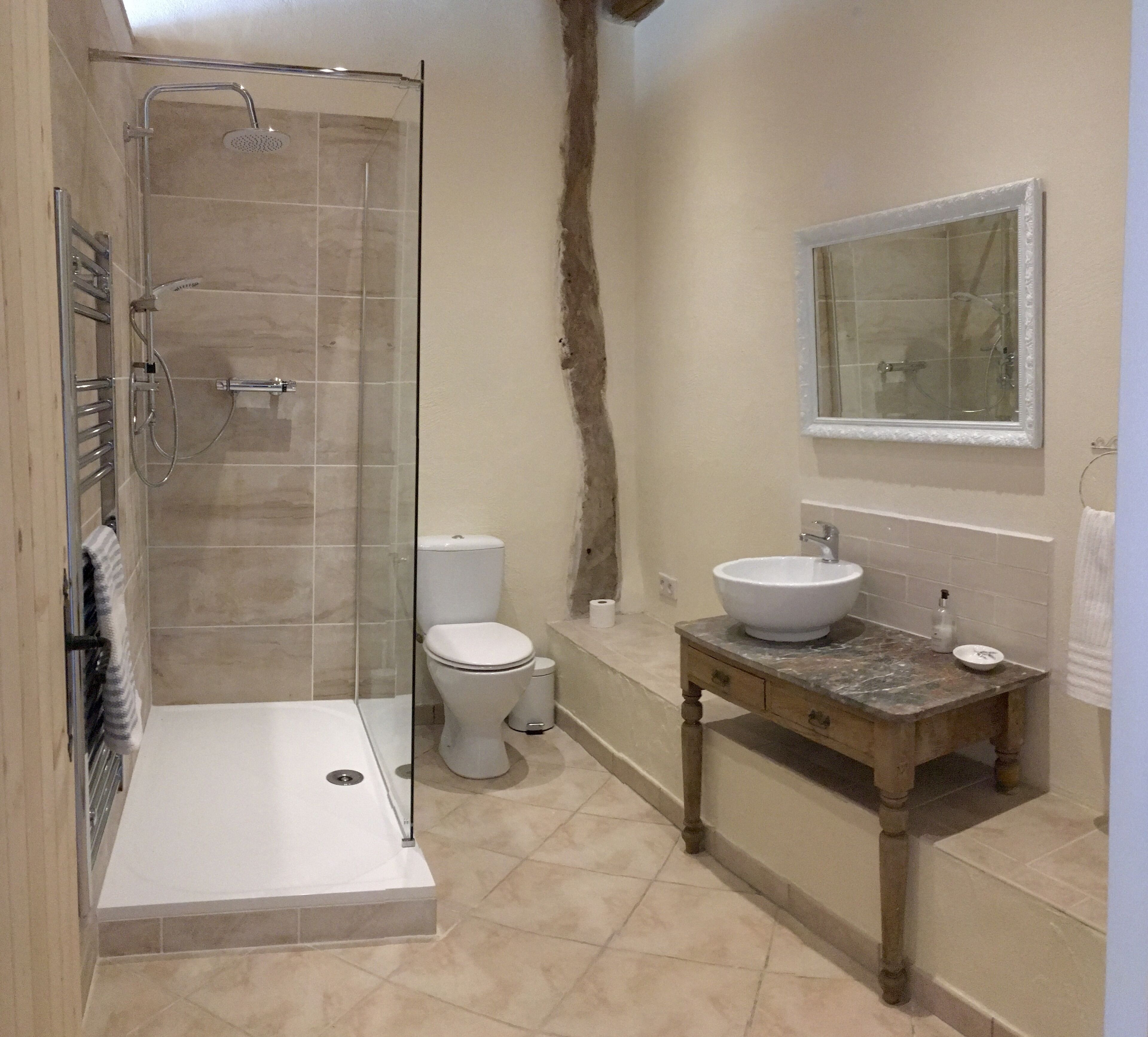 Ein Badezimmer mit einer gläsernen Duschkabine, Toilette und Waschbecken mit Marmorplatte.