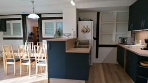 Une cuisine moderne dotée d’un îlot central, d’une table à manger en bois avec des chaises, et offrant une vue sur l’espace de vie.