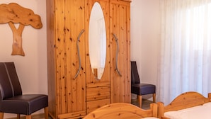 Une pièce comprenant une armoire en bois, deux chaises et un lit.