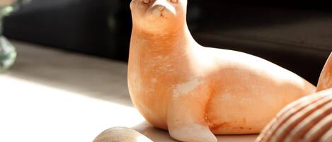 Una figurita de foca sobre una mesa con conchas marinas a su alrededor.