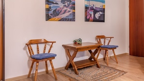 Une pièce avec deux chaises en bois, une petite table et deux tableaux accrochés au mur.