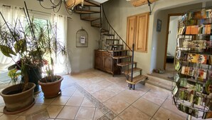 Una habitación amplia con una escalera espiral, vigas de madera y una estantería llena de libros.