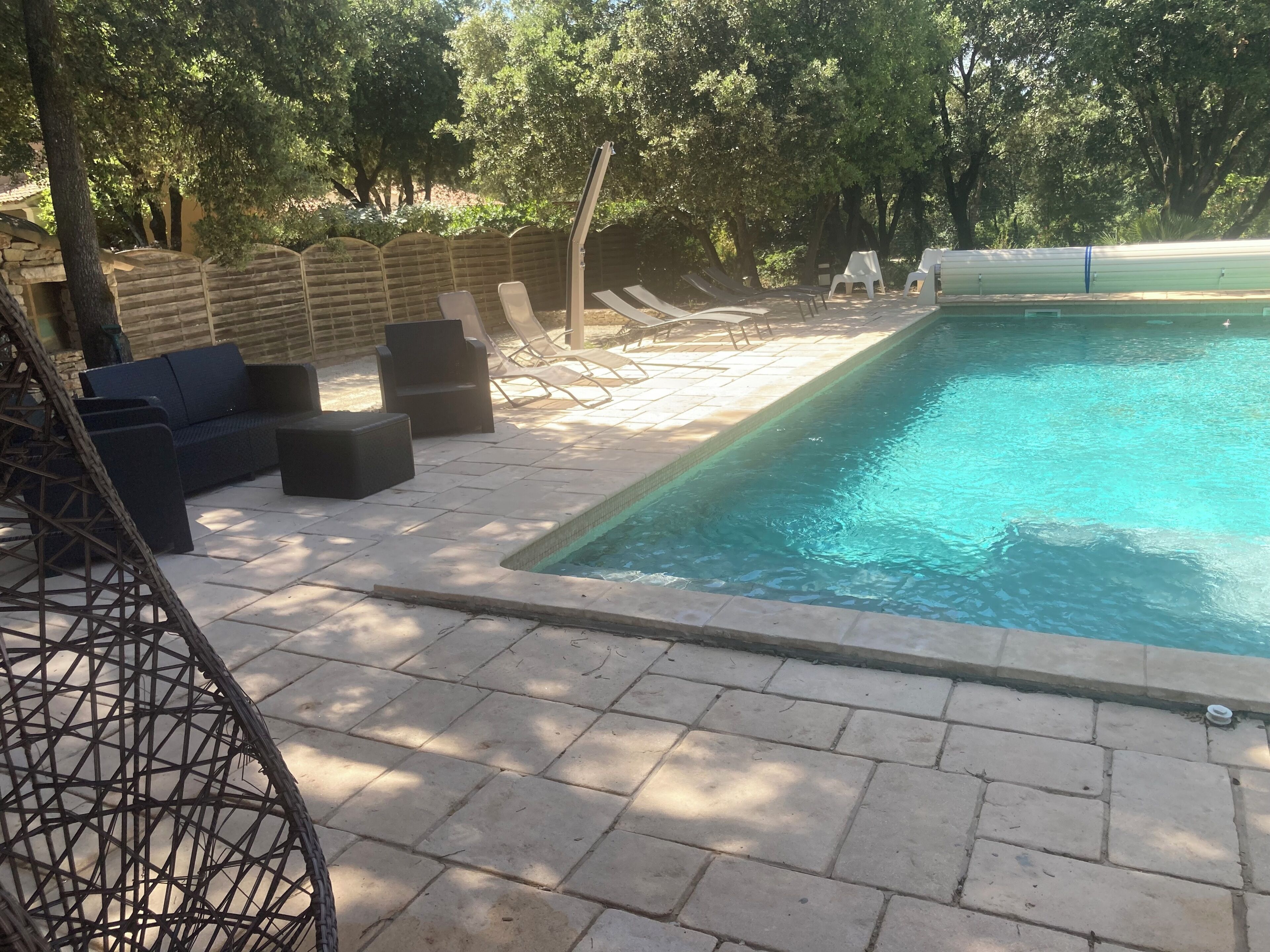 A swimming pool with lounge chairs and a wicker chair.