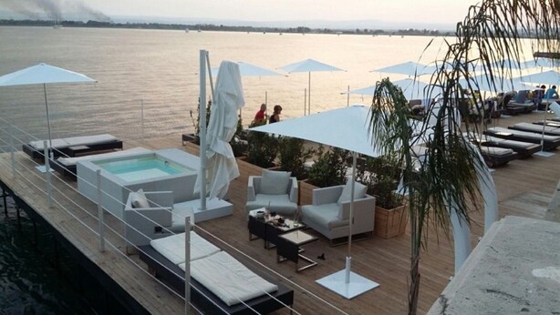 A deck with a pool, lounge chairs, and umbrellas overlooking a body of water. - Fully furnished apartment, with all comforts. ALL INCLUSIVE (Siracusa)