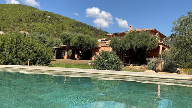 Una piscina con acqua cristallina, circondata dal verde e da un pendio.