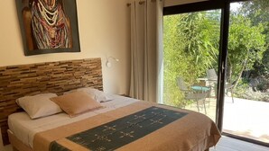 Una camera da letto con un letto, una testiera, una finestra e vista sul verde.