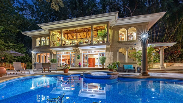 A two-story house with a swimming pool, outdoor seating, and a well-lit entrance. - Casa Bamboo | 4-Bedroom Colonial Jungle Villa | Private Pool | Manuel Antonio (Manuel Antonio)