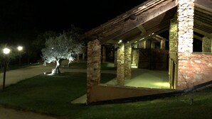 Un edificio de piedra con techo de madera, un pilar de piedra y un árbol en primer plano.