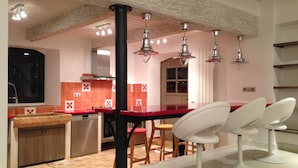 Una cocina moderna con encimeras rojas, una isla central e iluminación colgante.