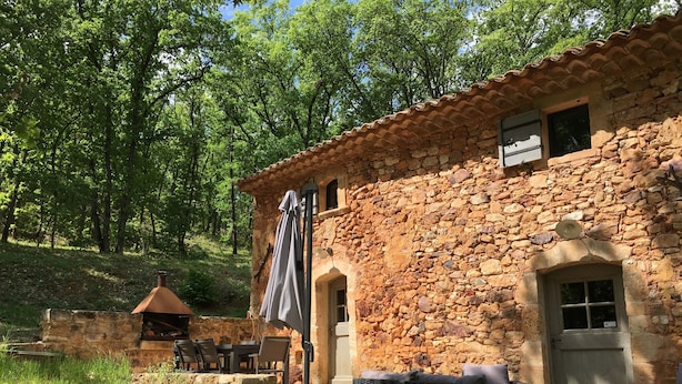 Un edificio de piedra con terraza y zona de barbacoa.