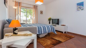 Ein modernes Schlafzimmer mit einem Bett, einem Fernseher, einer Lampe und einem Fenster mit Vorhängen.