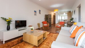 Ein modernes Wohnzimmer mit Sofa, Fernseher, Couchtisch und Dekorationselementen.